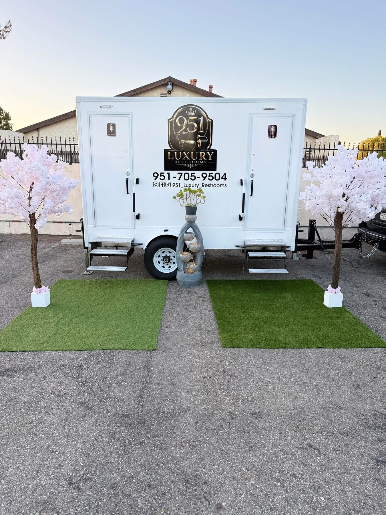 951 Luxury Restrooms trailer set up with cherry blossom trees, turf walkway and fountain